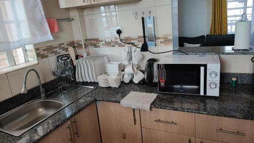 a kitchen counter with a sink and a microwave at Bliss Escapes in Ruiru