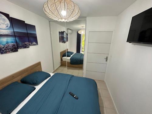 een slaapkamer met een blauw bed en een spiegel bij LOCATION T2 MEUBLÉ BAIE MAHAULT CONVENANCE in Baie-Mahault