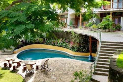 a swimming pool with a staircase next to a building at Modern Studio/Apt overlooking Pool/Ocean view in San Juan del Sur