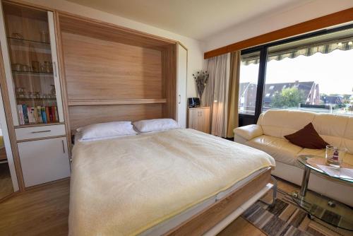 a bedroom with a large bed and a couch at Haus Jan am Strand Wohnung - 215 in Cuxhaven