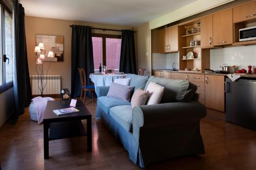 a living room with a blue couch and a kitchen at Apartaments Sant Bernat in Canillo
