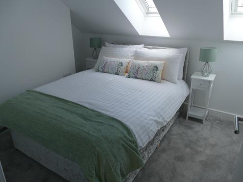 um quarto com uma grande cama branca e 2 almofadas em The Annexe em Eaglesham