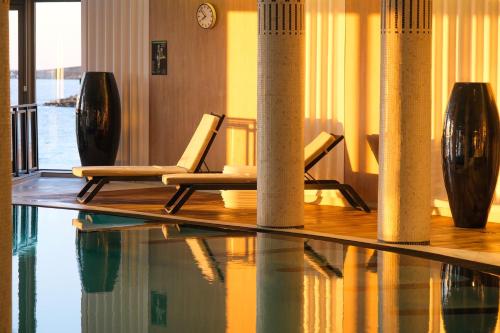 a lobby with two chairs and a table and a pool at Thalazur Saint Jean de Luz - Hôtel & Spa in Saint-Jean-de-Luz