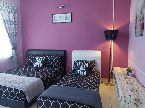 a bedroom with two beds and a purple wall at E&A Homestay KLIA/ Sepang/ Nilai in Sepang