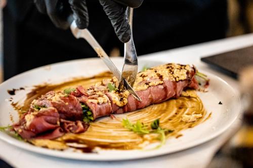 a person cutting a piece of meat on a plate at Union Plaza Hotel in Bucharest