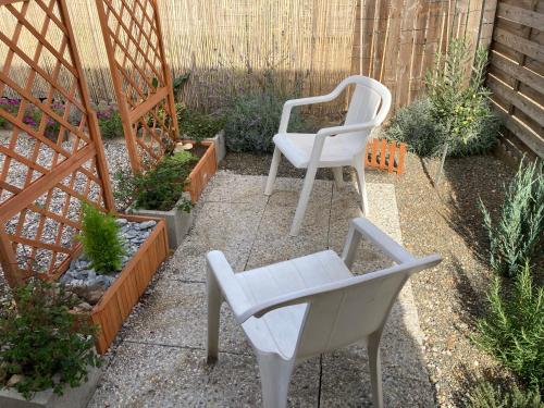 two white chairs sitting in a garden with plants at Studio atypique Le Mans in Le Mans