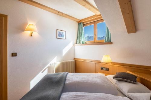 een slaapkamer met een bed en een raam en verlichting bij Häuslerhof App Larix in Villabassa