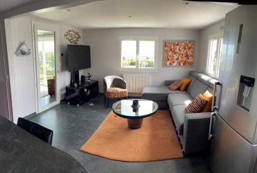 ein Wohnzimmer mit Sofa und Tisch in der Unterkunft Plage du Débarquement. Maison bord de Mer in Saint-Côme-de-Fresné