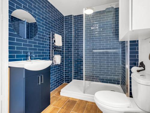ein blau gefliestes Badezimmer mit Toilette und Waschbecken in der Unterkunft Pass the Keys Spacious and Modern Sea Side apartment in Whitstable