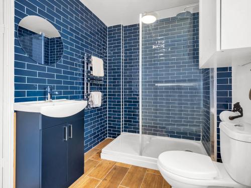 a blue tiled bathroom with a toilet and a sink at Pass the Keys Spacious and Modern Sea Side apartment in Whitstable