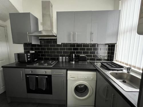 a kitchen with a washing machine and a sink at Leeds Serviced Accommodation in Killingbeck