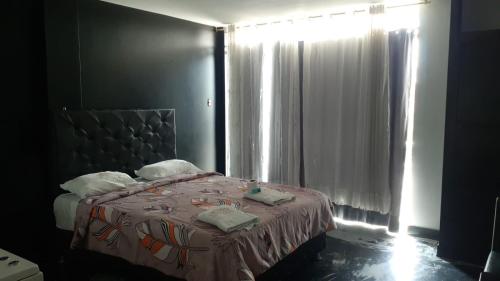 sypialnia z łóżkiem i oknem z zasłonami w obiekcie Venecia Hotel Larco w mieście Trujillo