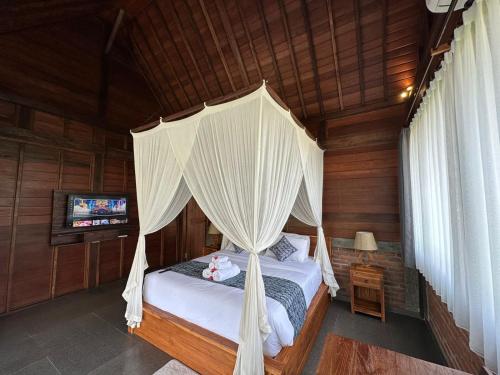 een slaapkamer met een hemelbed en een televisie bij SRILOKA VILLA1 in Ubud