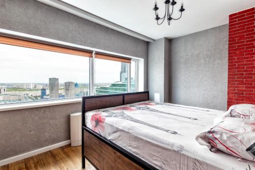 1 dormitorio con cama y ventana grande en Apartment Severnoye Siyaniye 37, en Astana