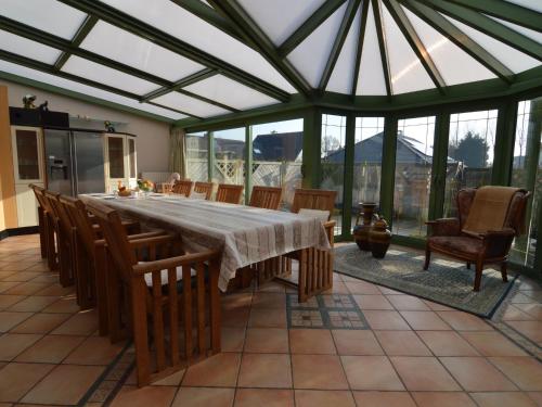 a large conservatory with a table and chairs and windows at Lavish Villa in Middelkerke with Sauna in Middelkerke