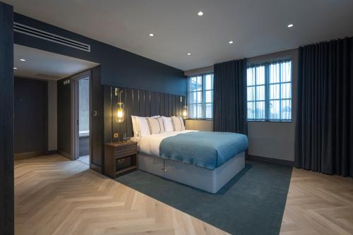 a bedroom with a bed with blue sheets and windows at The Heyford Hotel in Upper Heyford