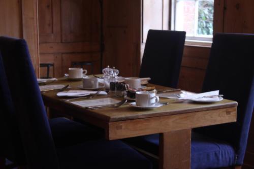a wooden table with cups and saucers on it at The Crown House Inn in Great Chesterford