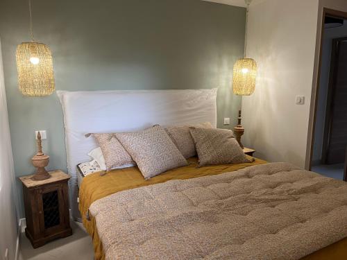 - une chambre avec un grand lit, des oreillers et deux lumières dans l'établissement Maison Le Citronnier avec piscine - Domaine E Case Di Cuttoli, à Cuttoli-Corticchiato