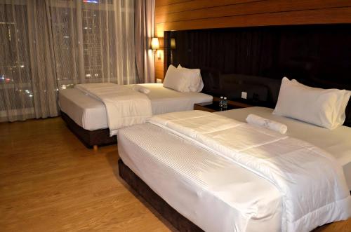 two beds in a hotel room with white sheets at Royal Suites At Dua Sentral in Kuala Lumpur