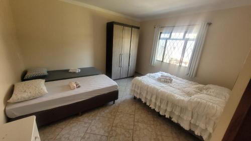 a bedroom with two beds and a window at Casa Feliz in Cascavel