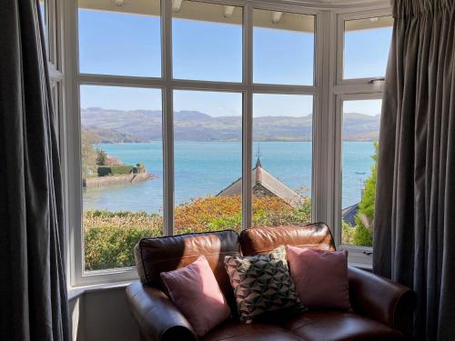 a couch sitting in front of a large window at Bryn Gwyn, Sleeps 8, Sea Views, Borth y Gest in Porthmadog