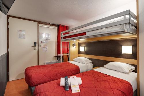 a hotel room with two beds with red sheets at Premiere Classe Bethune Fouquières Lès Béthunes in Fouquières-lès-Béthune