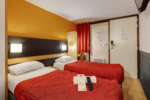 a hotel room with two beds with red sheets at Premiere Classe Bethune Fouquières Lès Béthunes in Fouquières-lès-Béthune