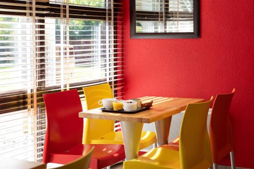 a dining room with a table and colorful chairs at Premiere Classe Bethune Fouquières Lès Béthunes in Fouquières-lès-Béthune