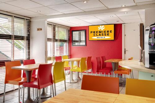 a restaurant with tables and chairs and a sign on the wall at Premiere Classe Bethune Fouquières Lès Béthunes in Fouquières-lès-Béthune