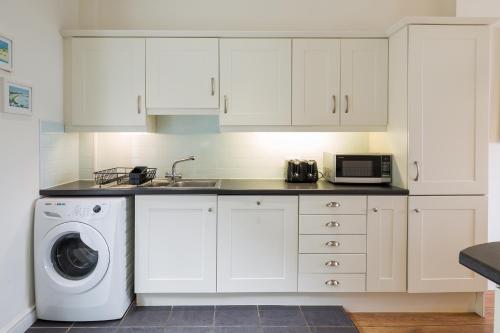 uma cozinha com uma máquina de lavar roupa e um lavatório em Bryn Gwyn, Sleeps 8, Sea Views, Borth y Gest em Porthmadog