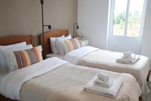 um quarto com 3 camas com toalhas brancas em Monte de Palma- Quinta Biodinâmica Momentos Únicos em Évora