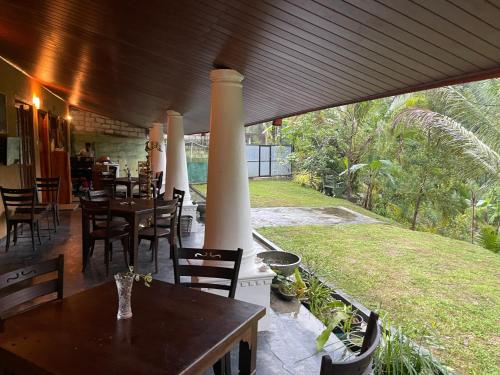 a restaurant with tables and chairs and a large window at Eagles Eco Lodge - Kandy in Digana