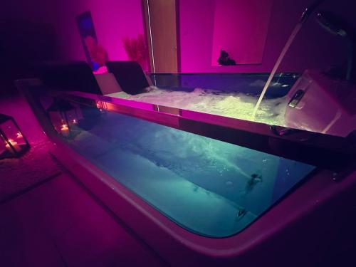 a swimming pool in a room with purple lights at Le Rêve d’une Nuit (suite CHARNELLE) in Réding