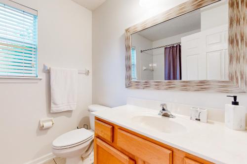 een badkamer met een wastafel, een toilet en een spiegel bij My Relaxing Place in Fleming Island