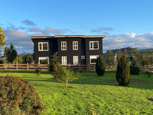 a large black house on a green field at Cabañas Los Aromos de Puerto Varas in Puerto Varas