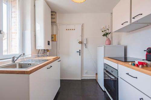 La cuisine blanche est équipée d'un évier et d'un réfrigérateur. dans l'établissement 2 chambres - Centre Gare, à Reims