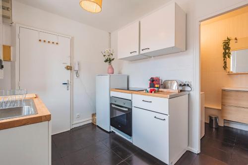 une cuisine avec des armoires blanches et un réfrigérateur blanc dans l'établissement 2 chambres - Centre Gare, à Reims