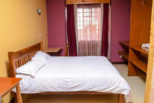 - une chambre avec un lit blanc et une fenêtre dans l'établissement The Penthouse Suites Serviced Apartments Meru, à Meru