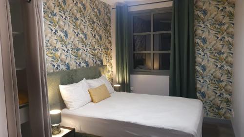 a small bedroom with a white bed with a yellow pillow at Les jardins de la rivière in Saint-Denis