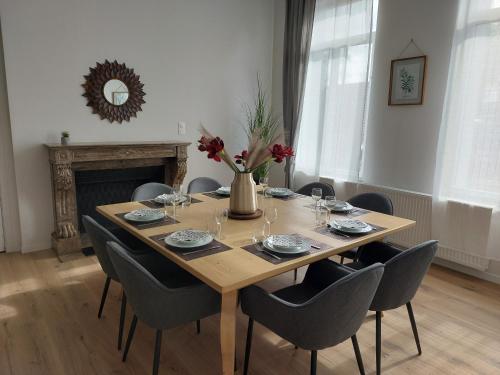 a dining room table with chairs and a vase of flowers at VILLA LOUISE B, B comme Belle Epoque in Saint-Amand-les-Eaux