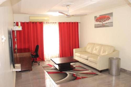 a living room with a white couch and red curtains at FREDA'S COURT in Accra
