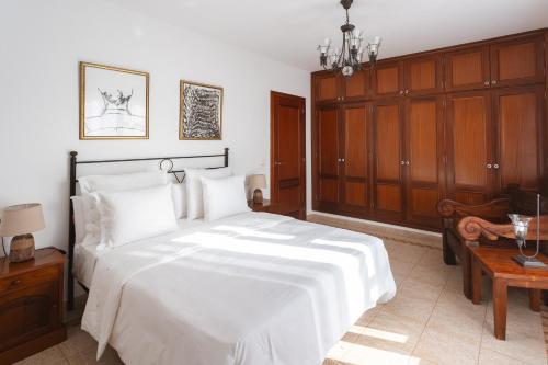 a bedroom with a large white bed and wooden cabinets at Casa Melián in Playa Blanca