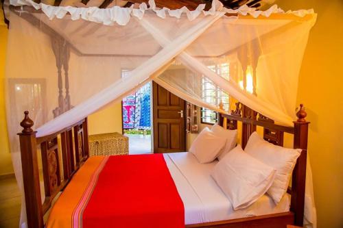 1 dormitorio con cama con dosel y almohadas rojas y blancas en Room Sawa, en Diani Beach