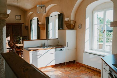 a kitchen with white cabinets and a sink and windows at Rittergut Hirschbach in Glashütte