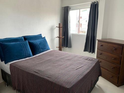 a bedroom with a bed with blue pillows and a window at Recanto da paz in Arraial do Cabo