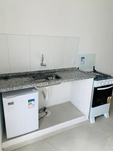 a white kitchen with a sink and a stove at Recanto da paz in Arraial do Cabo