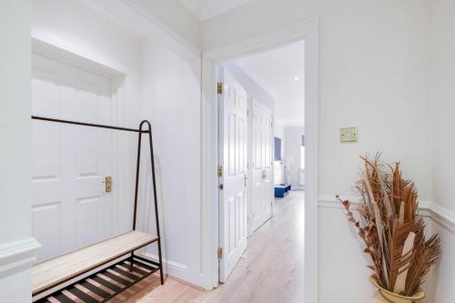 a hallway with white walls and a wooden bench at Modern, Bright, Spacious 2 Bed 2 Bath Barnet Penthouse By 360Stays in Barnet