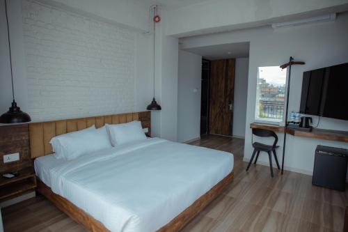 a bedroom with a bed and a desk and a television at Jade City Hotel in Pokhara