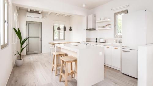 a white kitchen with a counter and stools in it at Bellevue Villas in Plaka