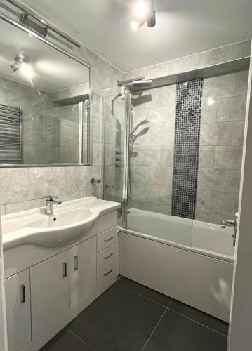 a bathroom with a sink and a tub and a shower at Modern Stylish Two Bedroom Apartment in Beckenham